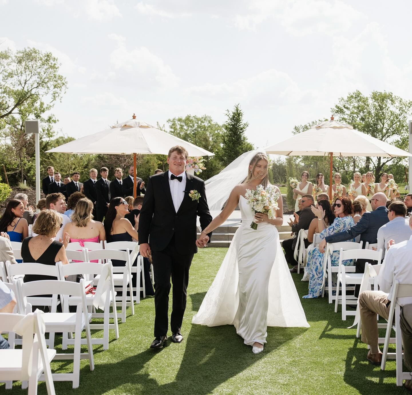 Outdoor wedding ceremony on lawn with white chairs and tent reception space