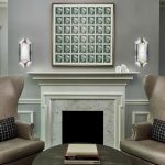 Symmetrical seating area with taupe wingback chairs, framed stamp collection above marble fireplace mantel