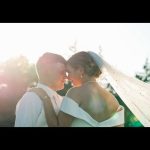 Bride and groom sharing intimate moment outdoors with veil flowing in golden sunlight