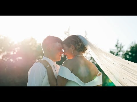 Bride and groom sharing intimate moment outdoors with veil flowing in golden sunlight