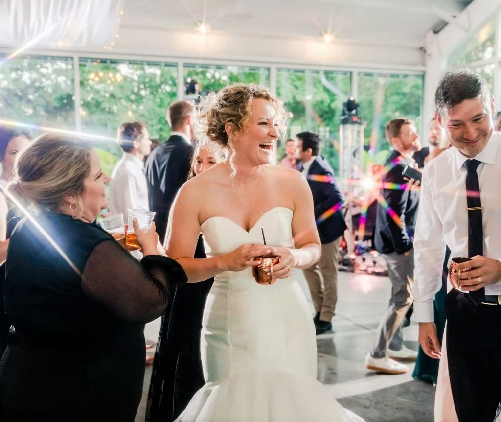 Bride laughing and celebrating with guests at indoor wedding reception