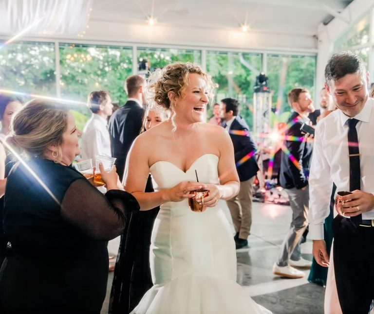 Bride laughing and celebrating with guests at indoor wedding reception