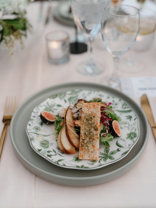 Plated chicken breast with roasted vegetables and greens served on speckled ceramic plate with rose gold flatware