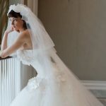 Bride in white wedding gown with flowing veil posing in elegant interior