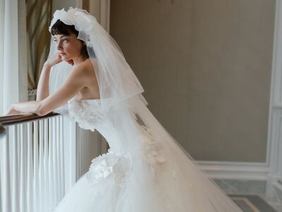 Bride in white wedding gown with flowing veil posing in elegant interior