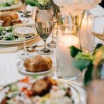Wedding reception table with salads, rolls, wine glasses, and candlelight