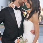 Bride and groom embracing in formal attire, holding a pastel spring bouquet on their wedding day