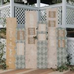 Geometric patterned seating chart display with "Find Your Seat" sign decorated with greenery garland