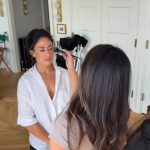 Makeup artist applying foundation to client in bright home studio setting