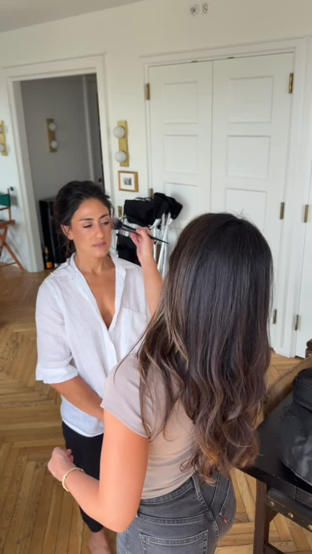 Makeup artist applying foundation to client in bright home studio setting