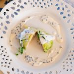 Artfully plated appetizer on decorative white pierced china with cream sauce and microgreens