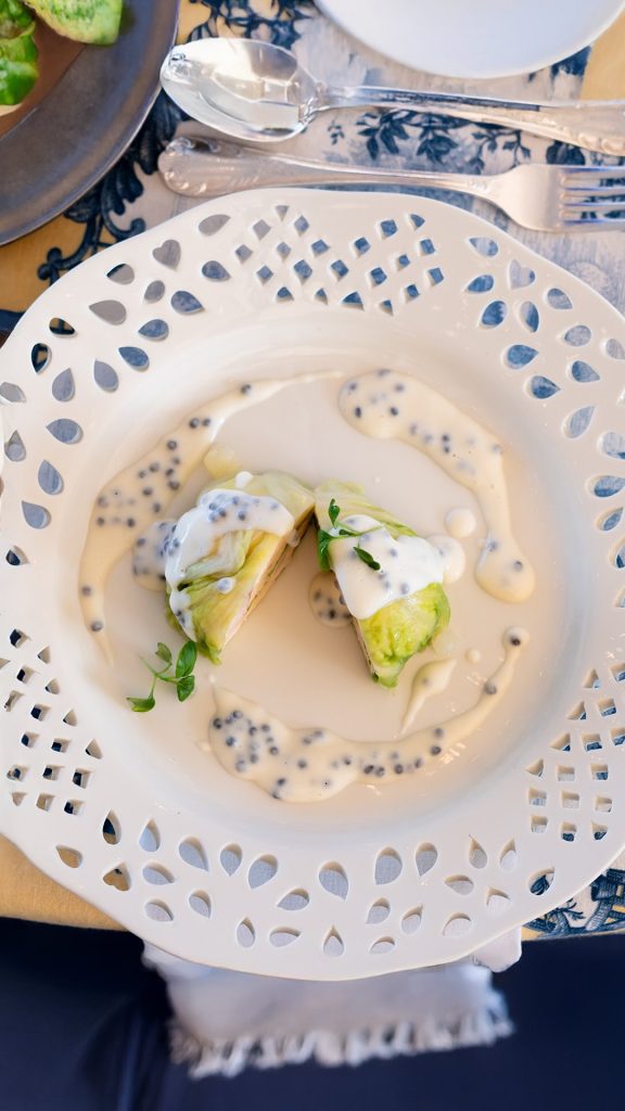 Artfully plated appetizer on decorative white pierced china with cream sauce and microgreens