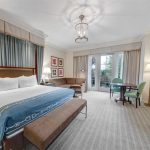 Spacious king guest room with plush bedding, work area, and private patio overlooking resort grounds
