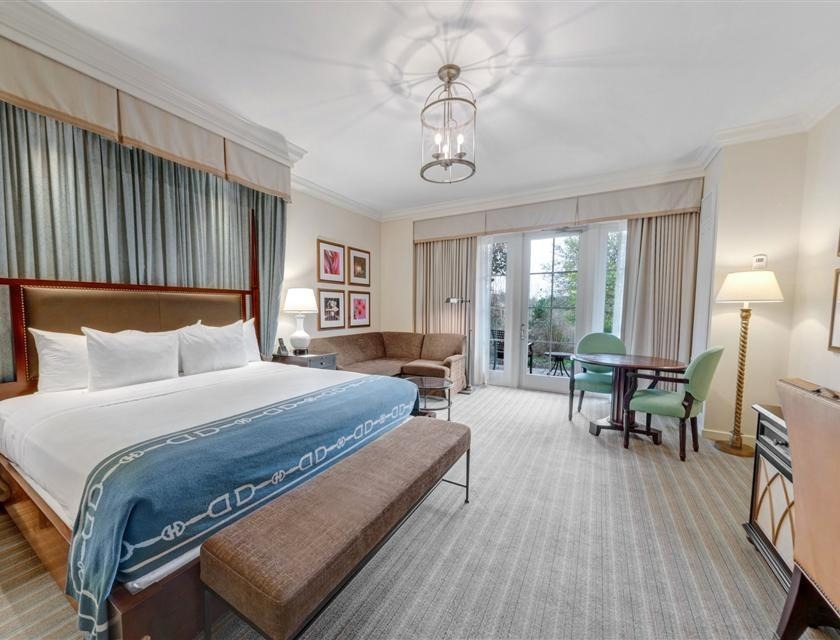Spacious king guest room with plush bedding, work area, and private patio overlooking resort grounds