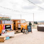 Orange retro Volkswagen photo booth van with wooden crates and props at wedding reception venue