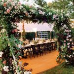 Outdoor wedding ceremony setup with floral arch and rows of chairs under trees