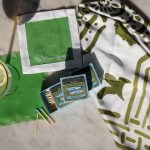 Green matchbooks and vintage-style favor tags displayed on white cloth with gold accessories