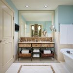 Luxurious spa bathroom with dual vanity, marble countertop, freestanding tub, and aqua blue walls
