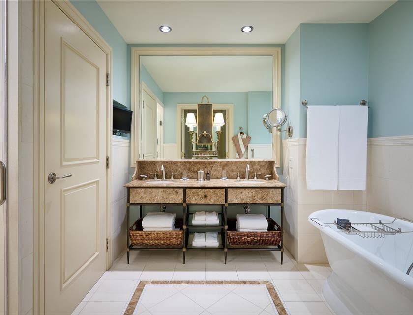 Luxurious spa bathroom with dual vanity, marble countertop, freestanding tub, and aqua blue walls