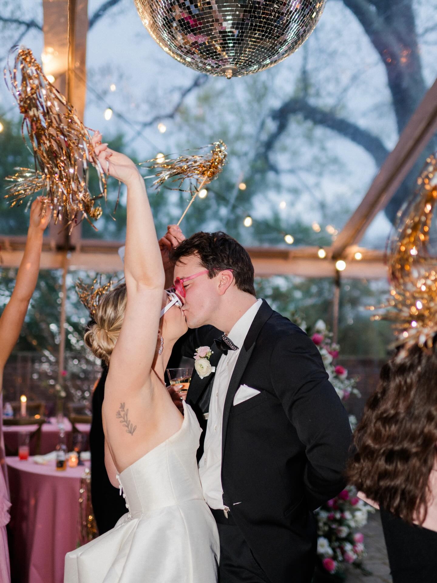 Bride and groom dancing together under string lights at evening wedding reception