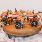 Individual charcuterie boxes arranged on wooden serving platter