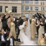 Bride and groom with wedding party celebrating on grand building steps, bridesmaids in gold gowns and groomsmen in black tuxedos