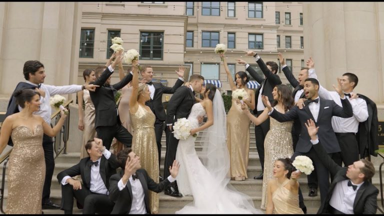 Bride and groom with wedding party celebrating on grand building steps, bridesmaids in gold gowns and groomsmen in black tuxedos
