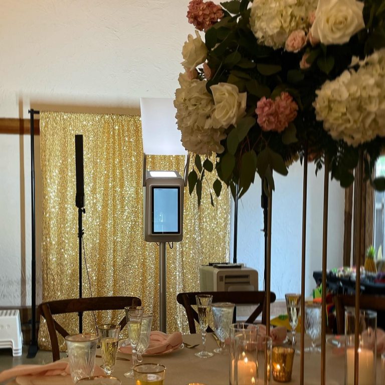 Elegant wedding reception table with tall floral centerpiece, gold sequin backdrop, and candles