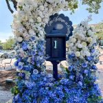 Decorative mailbox adorned with white and blue hydrangeas and roses forming an ombre floral display