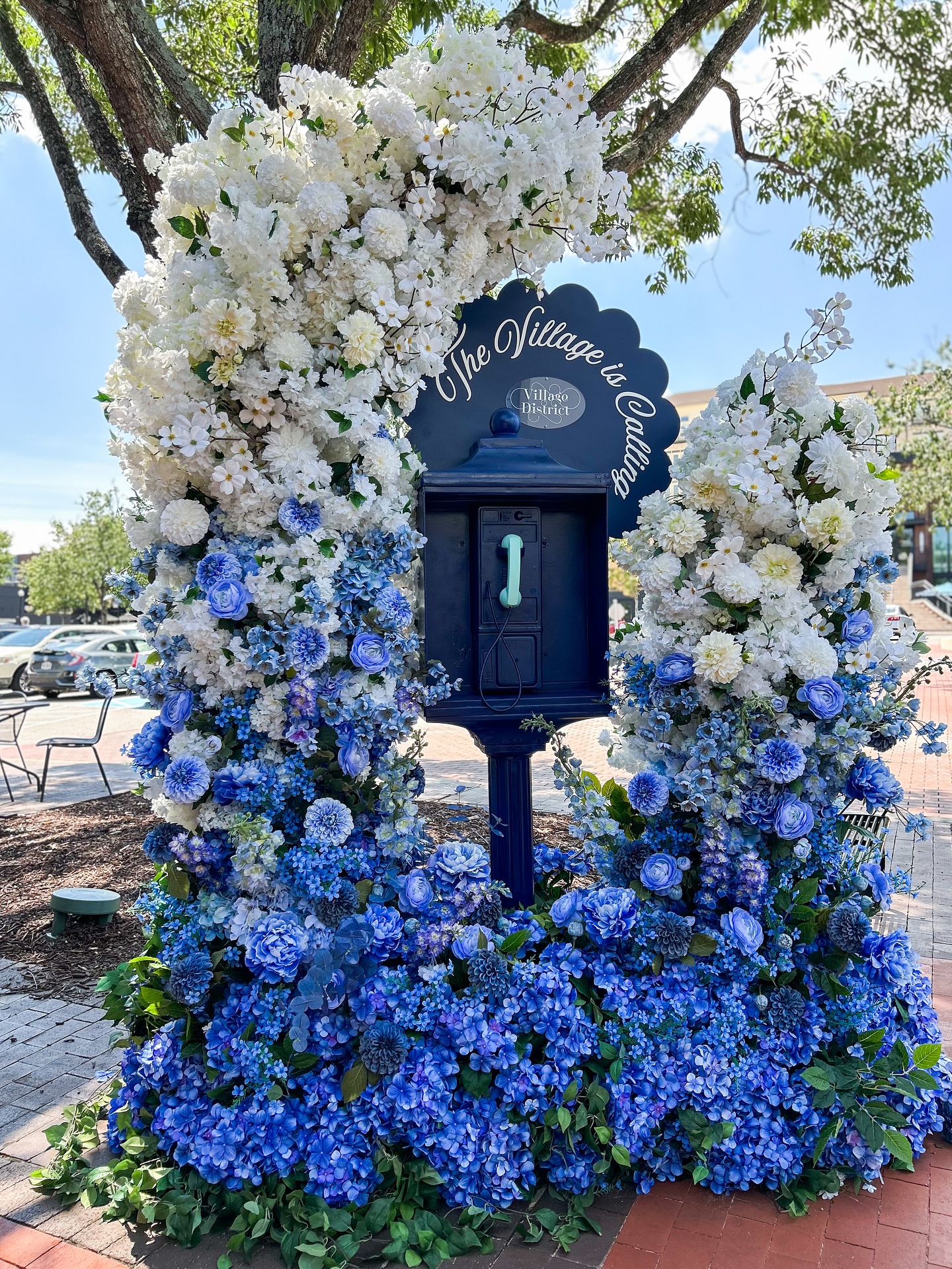Decorative mailbox adorned with white and blue hydrangeas and roses forming an ombre floral display