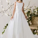 Classic A-line wedding gown with bateau neckline and full skirt surrounded by white orchid branches