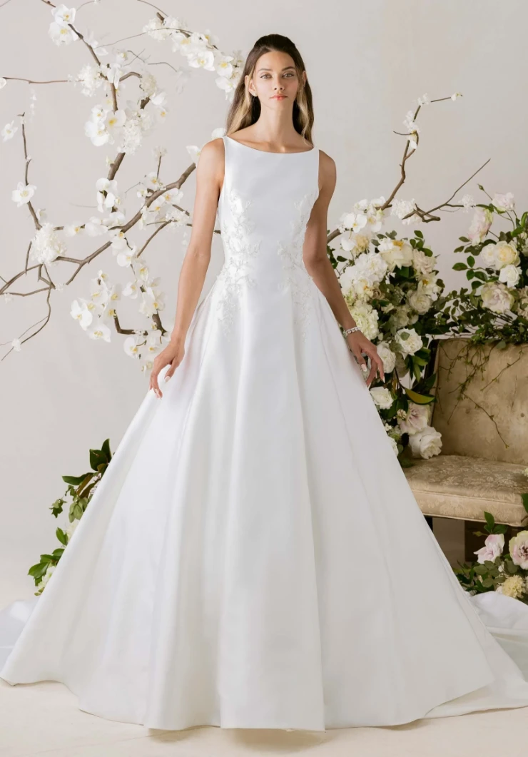 Classic A-line wedding gown with bateau neckline and full skirt surrounded by white orchid branches
