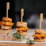 Mini slider appetizers stacked on wooden skewers with garnish