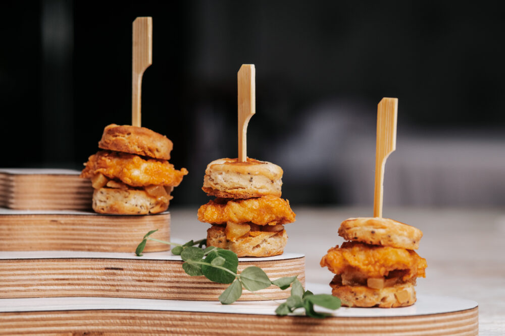 Mini slider appetizers stacked on wooden skewers with garnish