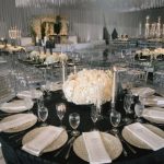 Luxurious reception with black tablecloths, white floral centerpieces, gold chargers, and crystal candelabras throughout ballroom