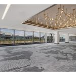 Large event ballroom with panoramic city views, geometric chandelier, and gray patterned carpeting