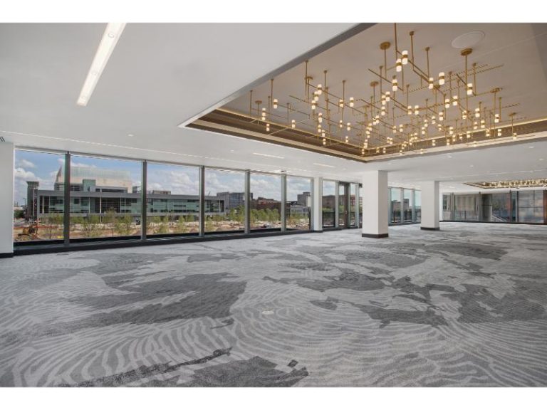 Large event ballroom with panoramic city views, geometric chandelier, and gray patterned carpeting