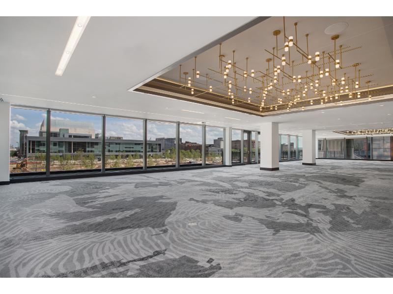 Large event ballroom with panoramic city views, geometric chandelier, and gray patterned carpeting