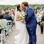 Bride and groom sharing first kiss at outdoor ceremony with guests and scenic Virginia landscape backdrop