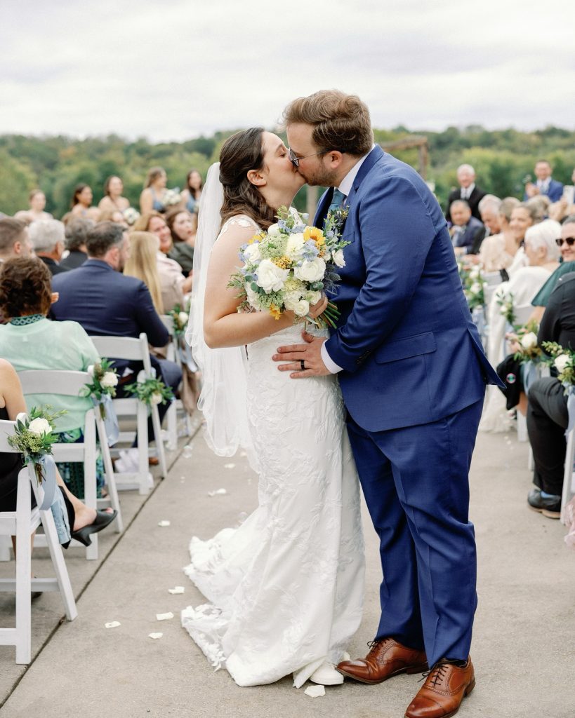 Bride and groom sharing first kiss at outdoor ceremony with guests and scenic Virginia landscape backdrop