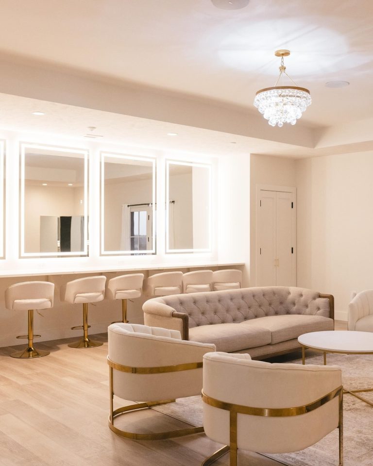 Luxurious bridal suite featuring curved velvet furniture, brass details, and illuminated vanity mirrors