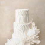 Three-tier white wedding cake with pearl beading and cascading white sugar flowers