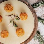 Golden-brown crab cakes arranged on white plate with herb garnish and rosemary sprigs