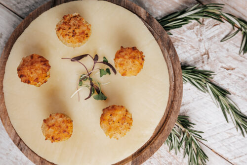 Golden-brown crab cakes arranged on white plate with herb garnish and rosemary sprigs
