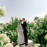Wedding couple standing together in peaceful garden setting with white hydrangeas