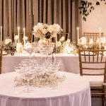 Tiered champagne glass tower with white roses and candles on reception table