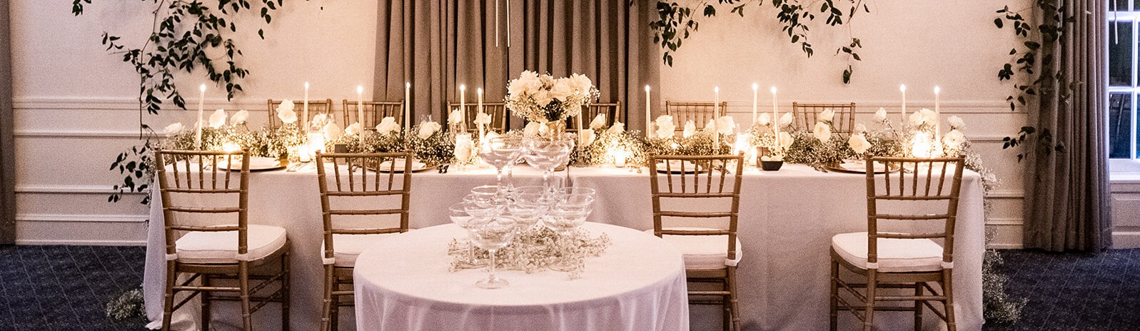Tiered champagne glass tower with white roses and candles on reception table