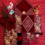 Burgundy wedding invitation suite with gold foil floral design, wax seals, vintage stamps, and red roses