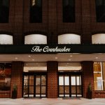 The Cornhusker illuminated entrance with brick facade and glass doors
