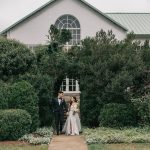 Bride and groom standing at entrance of ivy-covered building with arched window
